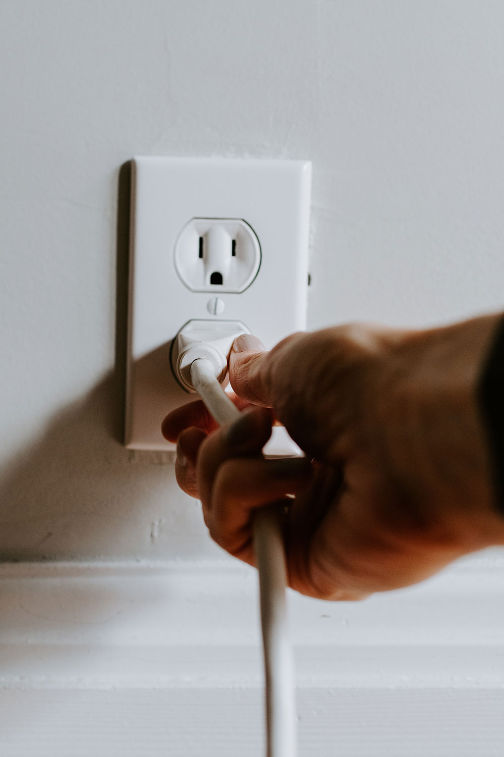 Person plugging in a cord into the wall.